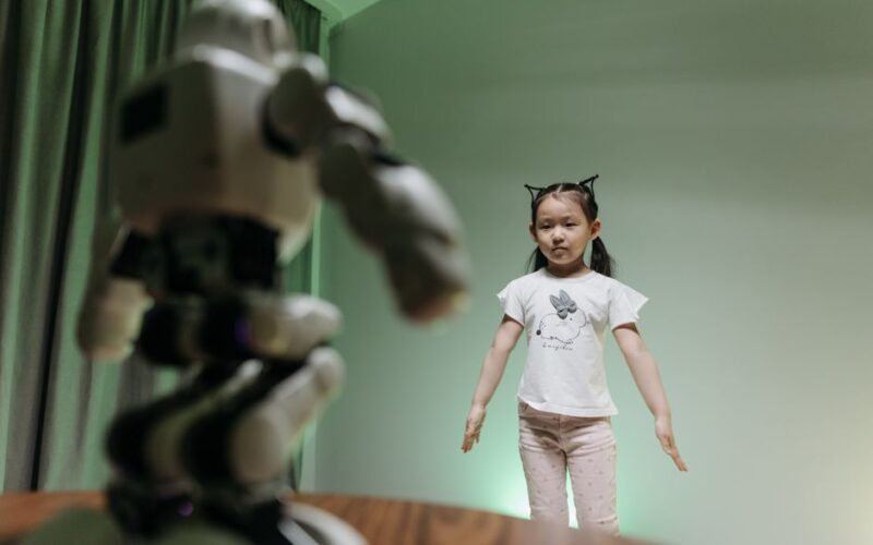 An Asian child interacts with a humanoid robot indoors, embracing innovation and play.