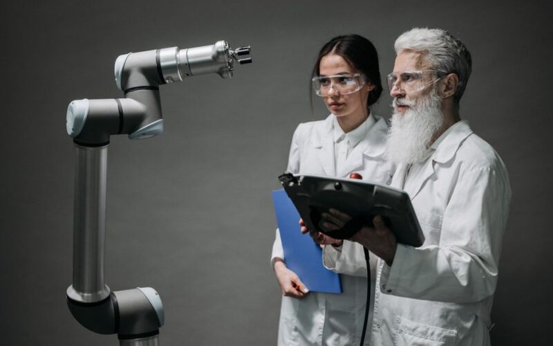 Researchers examining a robotic arm, showcasing technology and innovation.