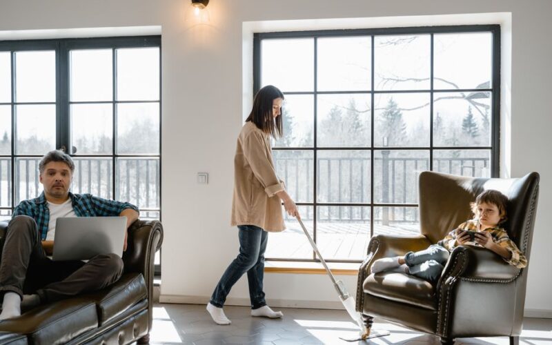 Family interacting in a sunlit living room, blending work, leisure, and chores.