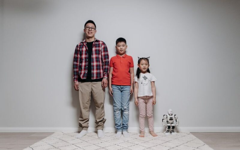 Father and children enjoying quality time with a robot. Indoor family bonding moment.