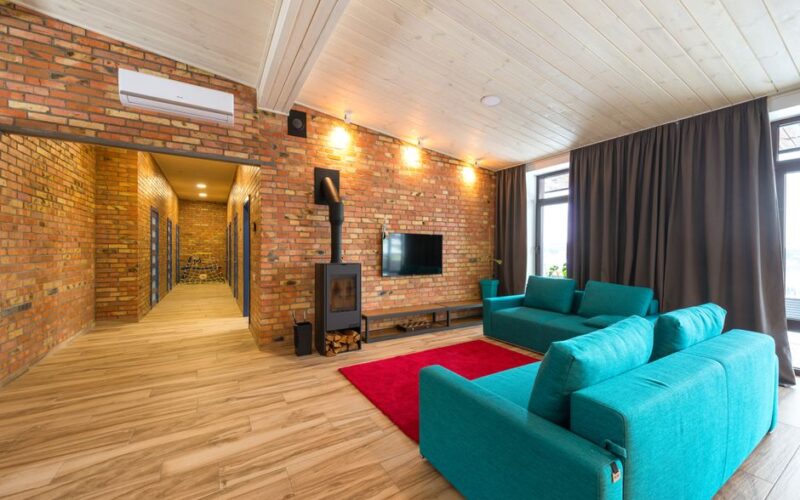 Spacious living room with blue sofas, red rug, and brick walls. Cozy and contemporary interior.