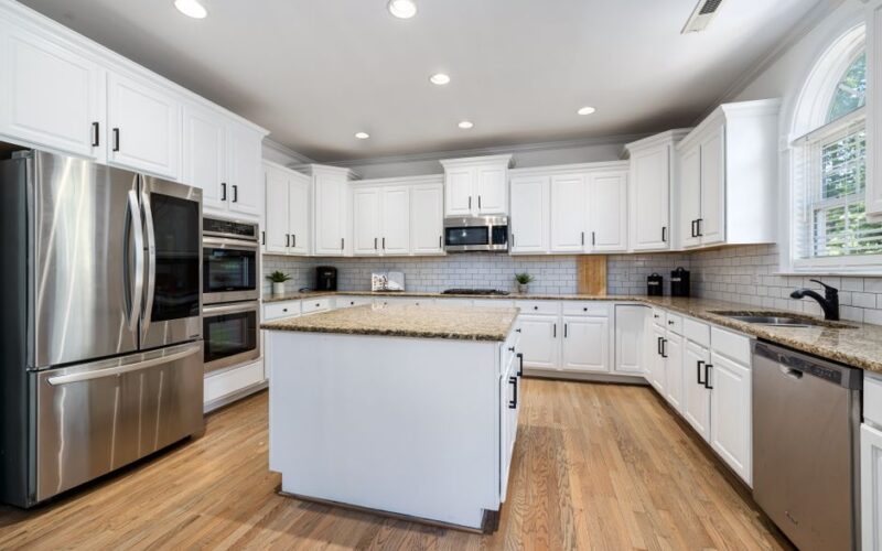 Modern kitchen featuring white cabinets, granite countertops, and stainless steel appliances.