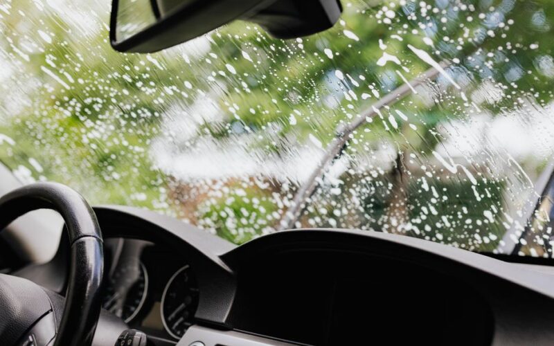 Interior view of a car with soapy windshield during cleaning. Clear dashboard visible.