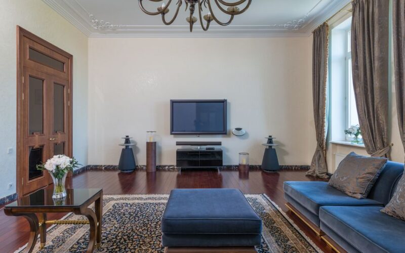 Interior of modern lounge with TV and carpet with patterns under chandelier in daytime