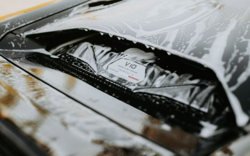 Detailed image of a sleek car being washed with foam, showcasing the car's design and cleanliness.