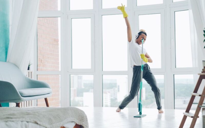 Woman enjoying cleaning while dancing with headphones. Bright and joyful scene.