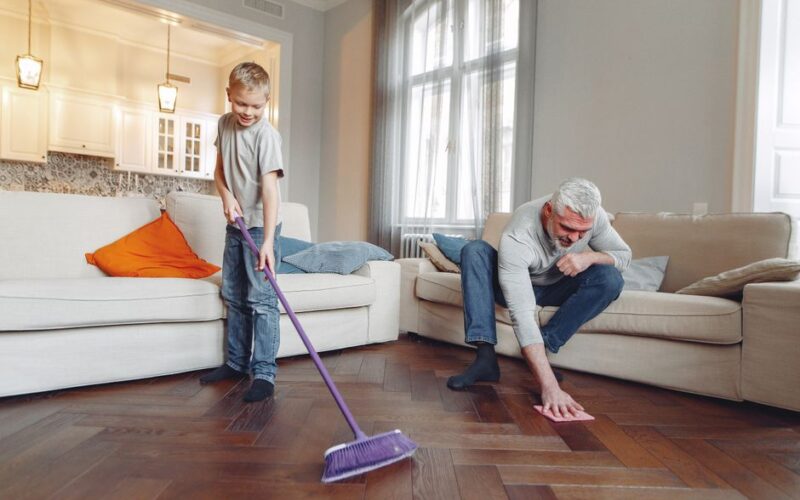 A grandfather and grandson enjoy quality time cleaning their living room together.