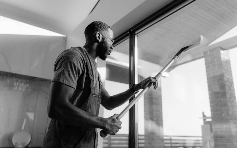 A professional cleaner wiping large glass panels with precision inside a modern building.