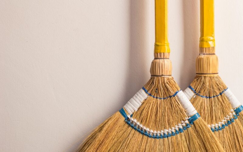 Pair of traditional Filipino walis tambo brooms on a neutral wall for home cleaning.