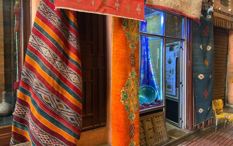 Vibrant handmade rugs hanging in a Taroudant market showcasing Moroccan craftsmanship.