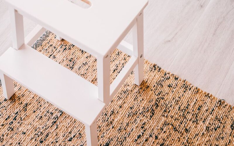 A clean, minimalist stepladder on a natural woven rug in a stylish interior.