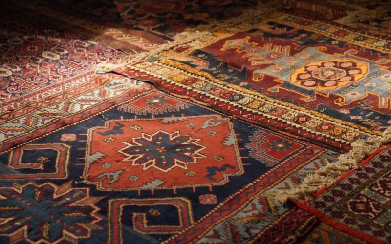 A detailed view of colorful Persian carpets with intricate geometric and floral patterns, highlighting vintage design.