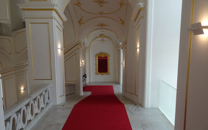 Luxurious interior of a Bratislava castle with a red carpeted hallway and ornate ceiling.