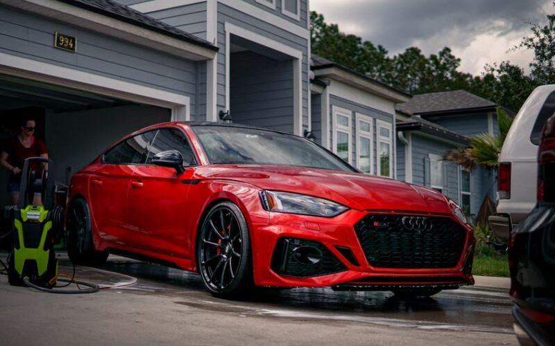 A vibrant red Audi RS5 parked in a residential driveway, freshly cleaned and exuding sportiness.