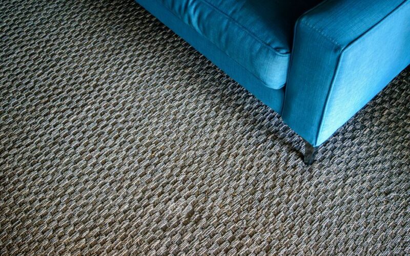 A modern blue sofa corner on a textured woven carpet, capturing a minimalist design.