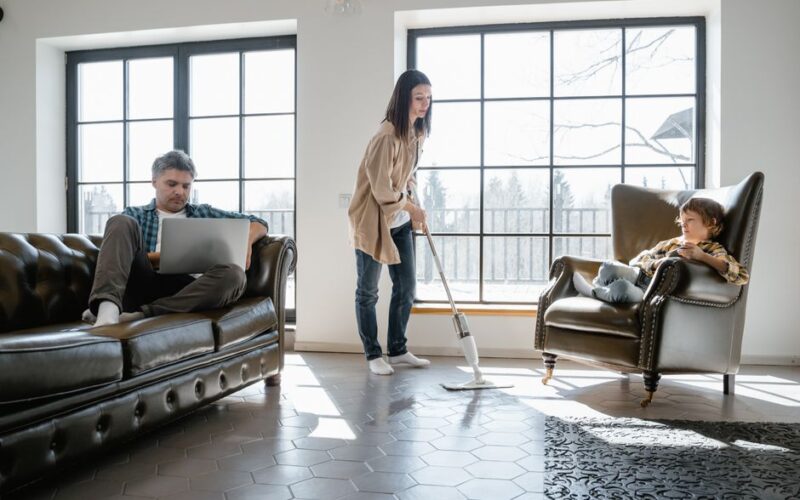 Family scene depicting vacuuming, working, and relaxing in cozy living room with natural light.