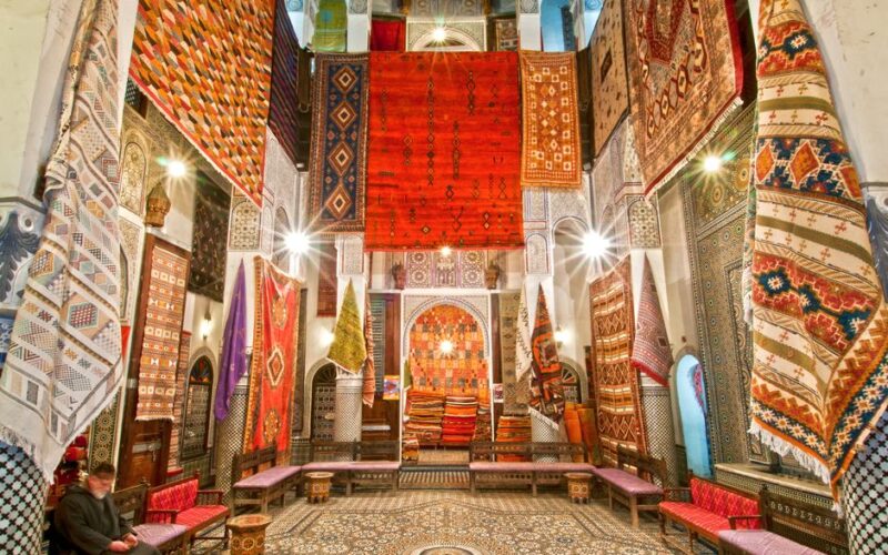 Stunning display of traditional Moroccan carpets in a Fès shop, showcasing vivid colors and intricate patterns.