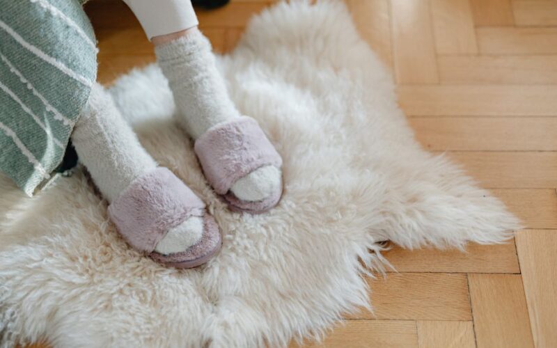 Warm and cozy feet in plush slippers resting on a soft fur rug for relaxation.