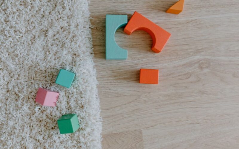 Close-up of colorful wooden blocks on a carpet and wooden floor.