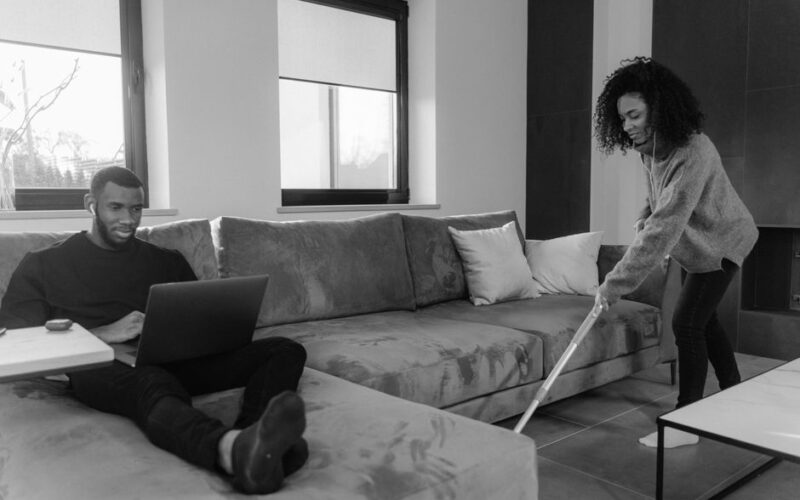 Engaged in cleaning and remote work, a couple maintains a cozy home environment.
