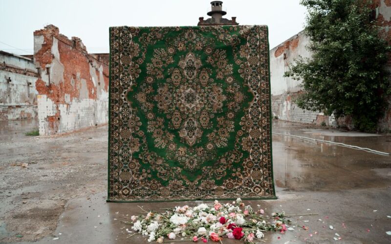 A detailed green carpet displayed against a rustic backdrop with scattered flowers.