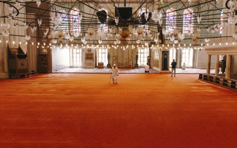 Beautiful interior view of Selimiye Mosque in Istanbul with ornate chandeliers and vibrant red carpet.