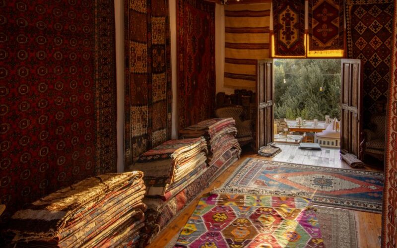Warmly lit room showcasing vibrant traditional rugs with an inviting open view.