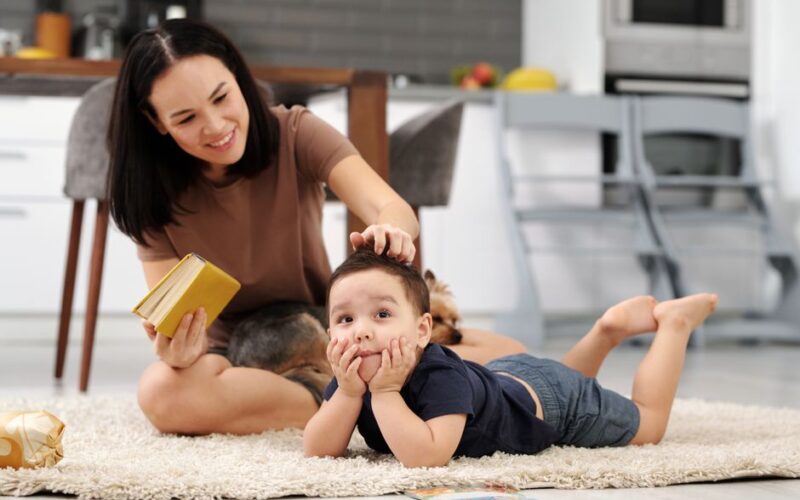 A mother and child bonding over a book while relaxing on the carpet in a cozy home setting.
