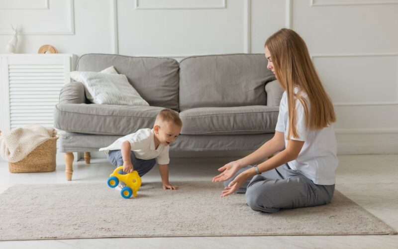 A mother and her baby interact on a cozy living room carpet, showcasing family bonding.