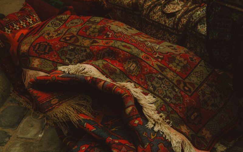 Vibrant Azerbaijani carpets stacked in a Baku marketplace showcasing intricate designs.