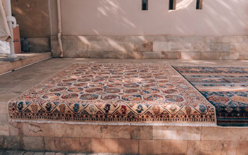 Elegant traditional rugs displayed in a sunlit Bukhara courtyard.