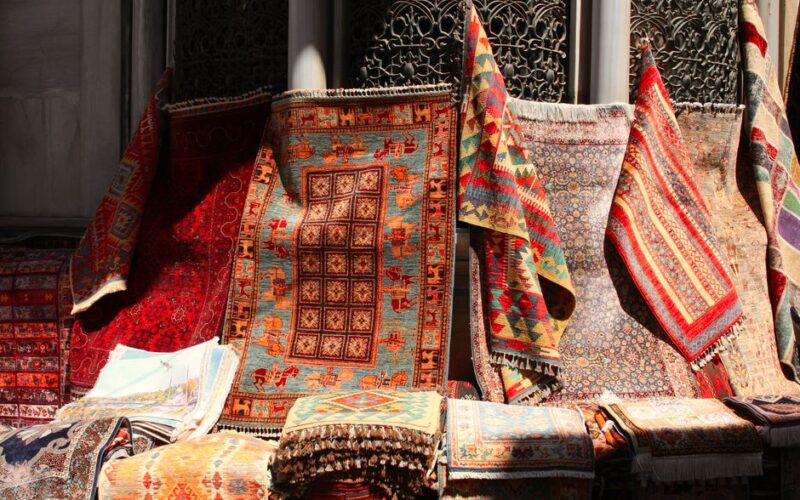 A colorful assortment of traditional oriental rugs in sunlight, showcasing intricate patterns.