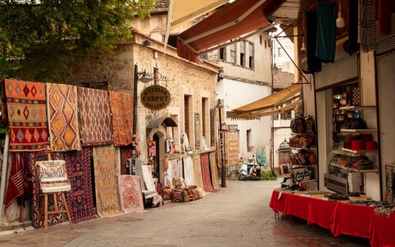 Explore the vibrant street market in Antalya with colorful carpets and traditional stalls.