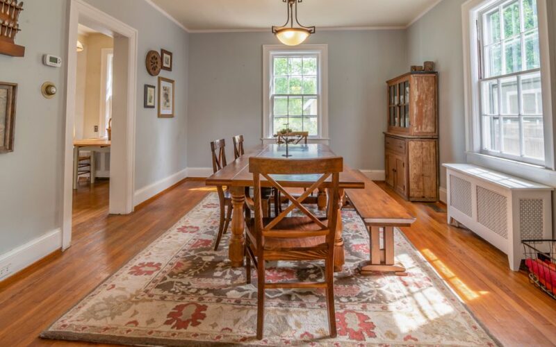 Bright dining room with wooden furniture, vintage carpet, and classic decor.