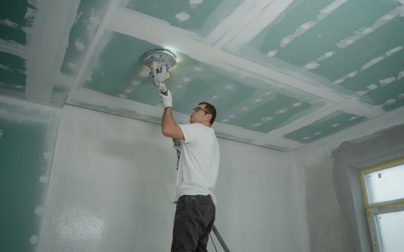 A worker expertly polishes a ceiling indoors, demonstrating home renovation skills.