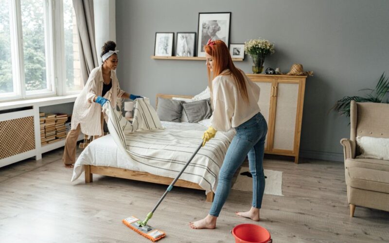 Two women cleaning their bedroom, highlighting daily life in a modern, cozy setting.