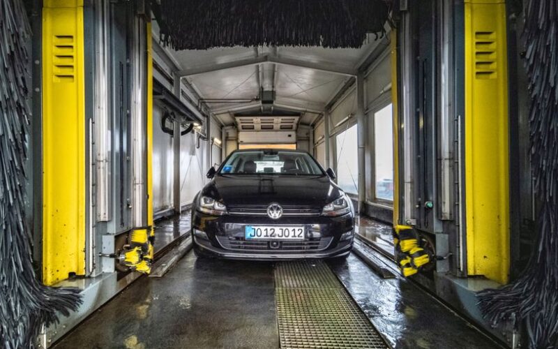 A black car undergoing a thorough cleaning in an automated car wash facility.