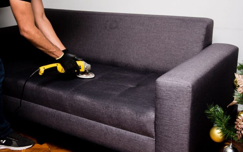 A professional performs sofa cleaning with a grinder in an indoor setting, showcasing efficient service.