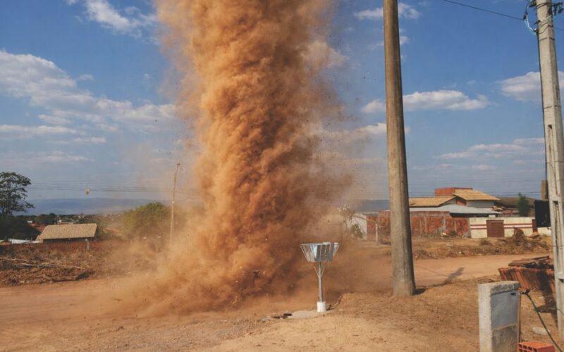 Impressive dust devil swirling on an open road in Tocantins, Brazil under a clear blue sky.