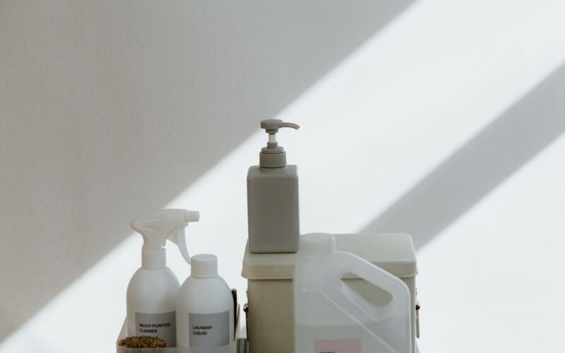 A collection of cleaning products on a minimalist background with dramatic shadows.