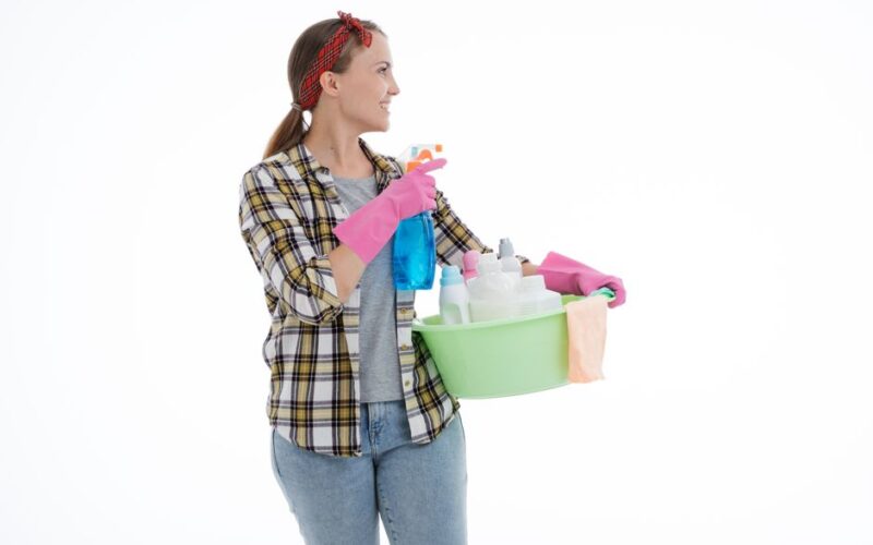 Woman holding cleaning supplies in a studio shot with a white background. Perfect for housekeeping themes.